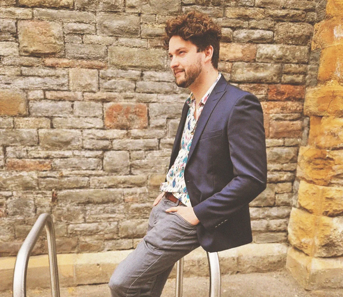 A member of the As Intended team leaning against a stone wall